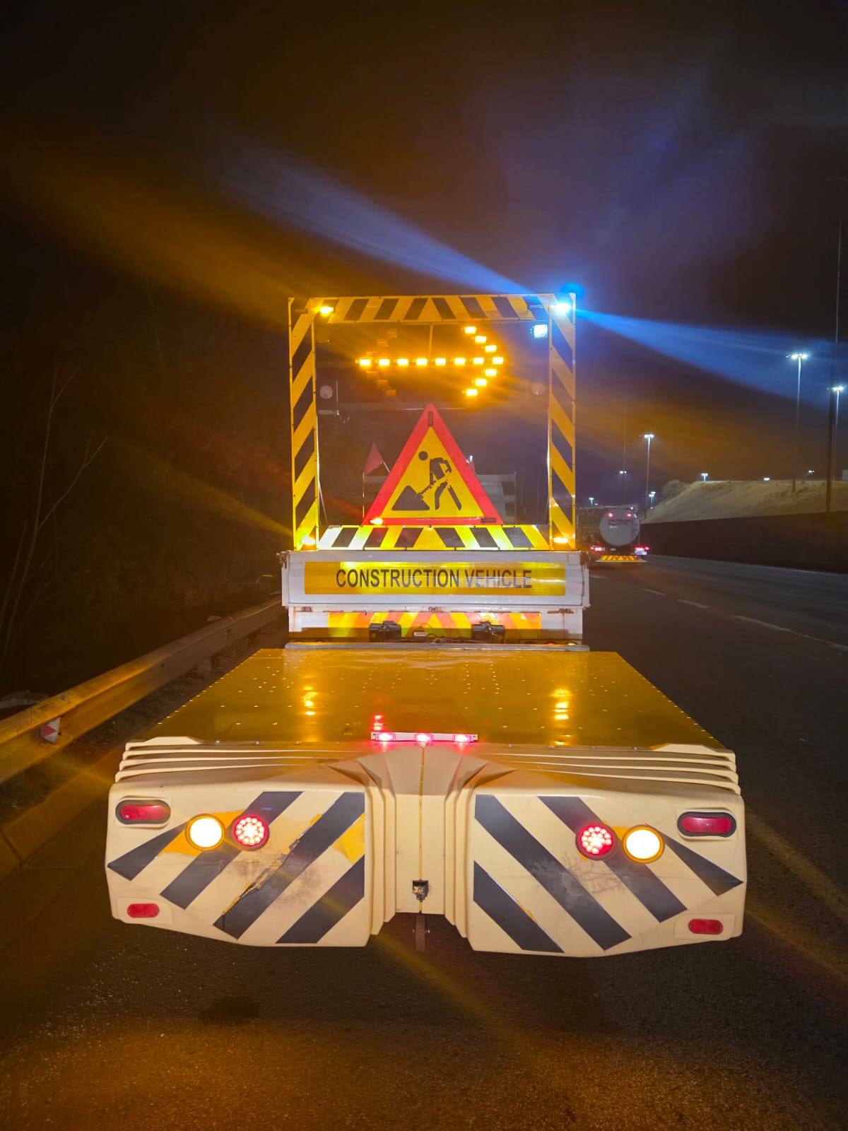 Construction vehicle with illuminated arrow board working at night